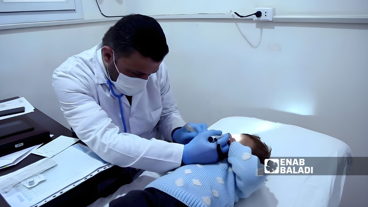 طبيب يفحص طفلًا بأحد عيادات رأس العين - 6 أيلول 2025 ()