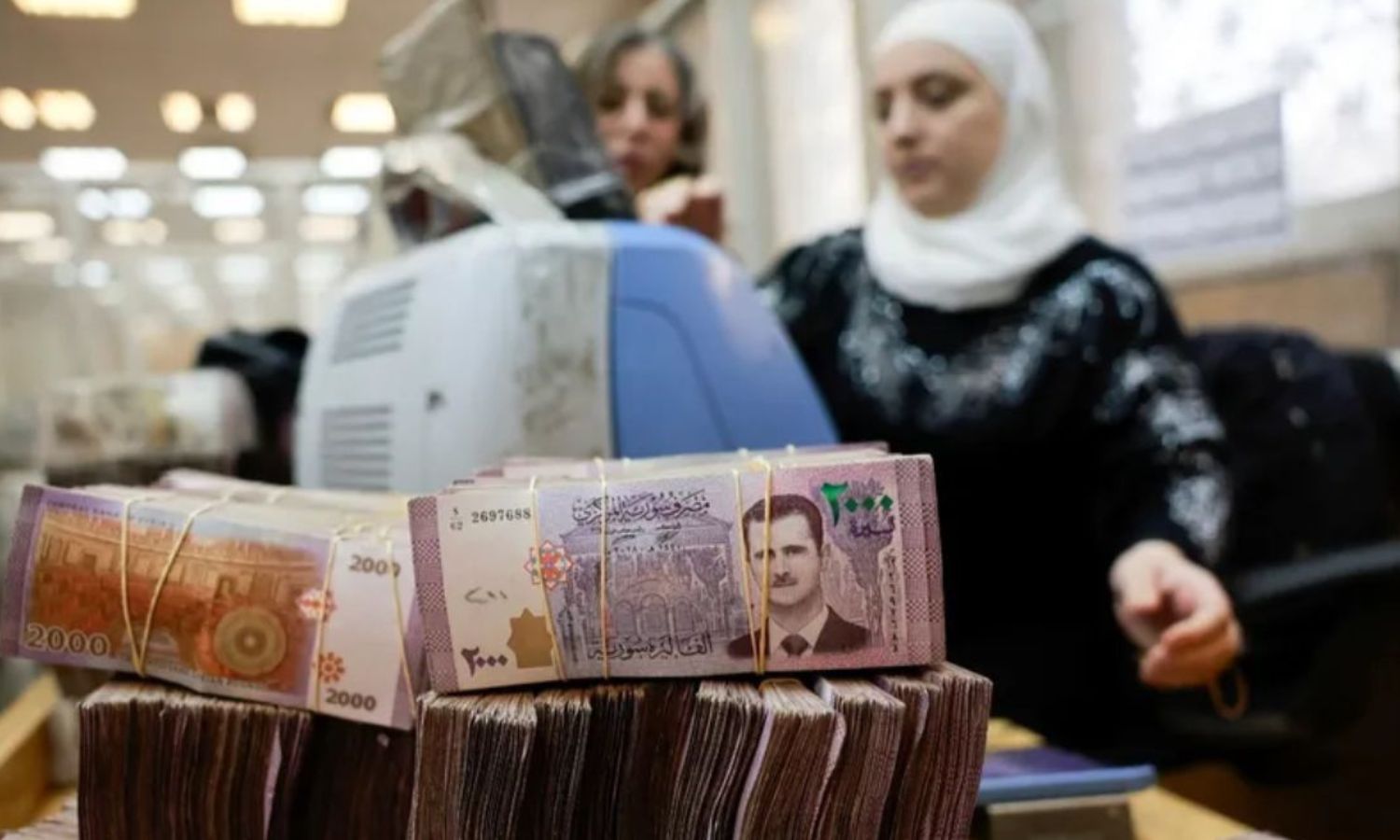 رزم من الأوراق النقدية السورية بينما تقوم موظفة بعدّ النقود في البنك المركزي السوري - 16 كانون الأول 2024 (رويترز)