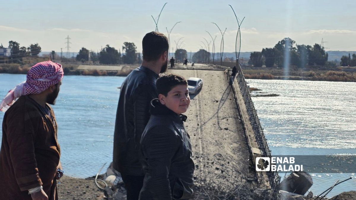 مدنيون يقفون أمام جسر الرشيد في الرقة شمالي سوريا بعد تدميره جراء العمليات العسكرية بين الجيش السوري وقوات سوريا الديمقراطية - 19 كانون الثاني 2026 (/إياد عبد الجواد)