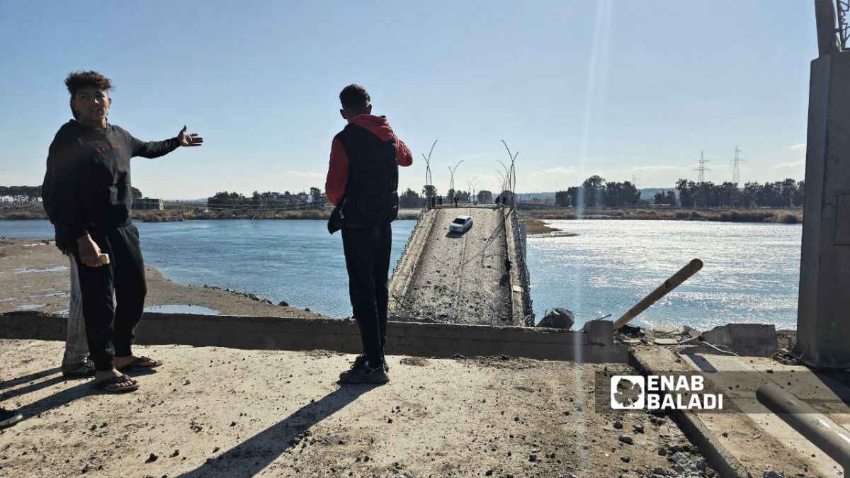 مدنيون يقفون أمام جسر الرشيد في الرقة شمالي سوريا بعد تدميره جراء العمليات العسكرية بين الجيش السوري وقوات سوريا الديمقراطية - 19 كانون الثاني 2026 (/إياد عبد الجواد)